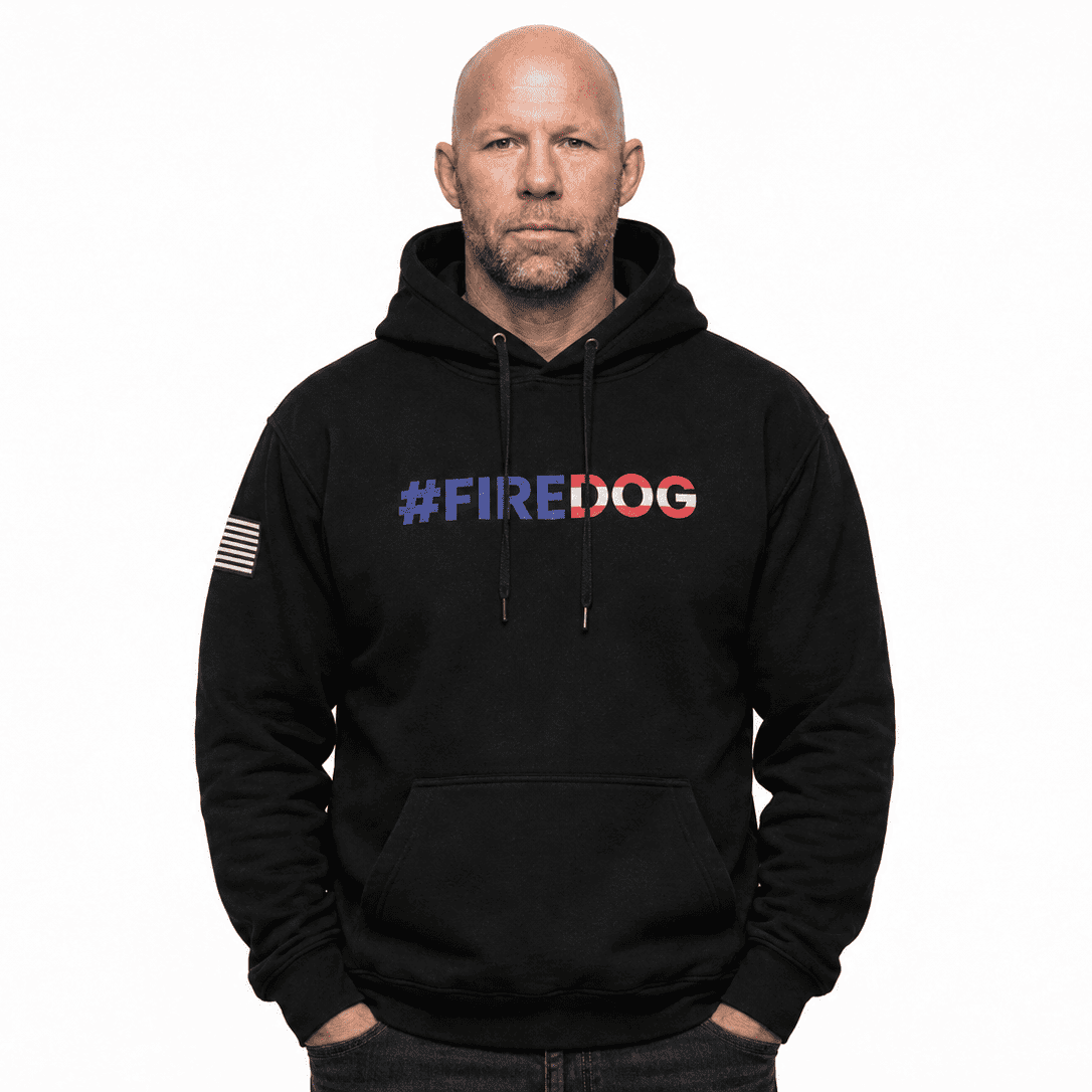 A bald man wearing a black pullover hoodie with '#FIREDOG' printed across the chest in red, white, and blue, and an American flag patch on the sleeve, against a plain white background.